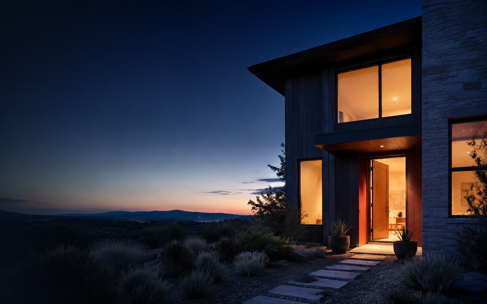 A warmly lit home with an open front door at dusk